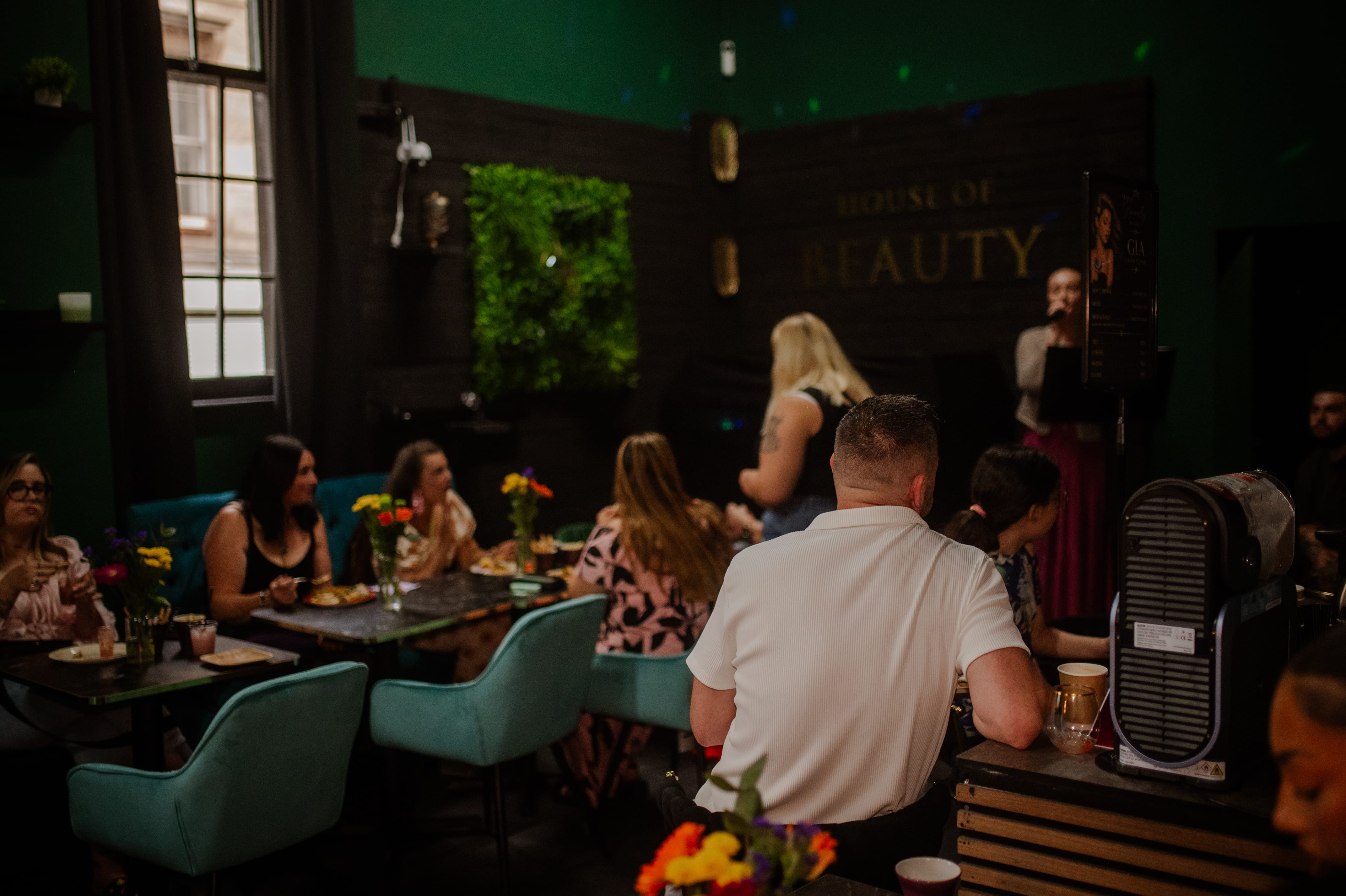 The emerald room full of guests beneath the gold House of Beauty sign